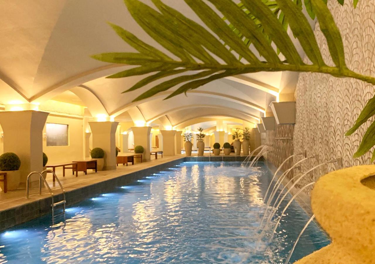 Buona Vitta Gramado Resort & Spa By Gramado Parks Exterior photo The photo shows an indoor swimming pool with a serene and elegant atmosphere. The pool has a calm blue water surface, illuminated by soft lights along its edges. The architectural design features arches in the ceiling, creating an open and spacious f