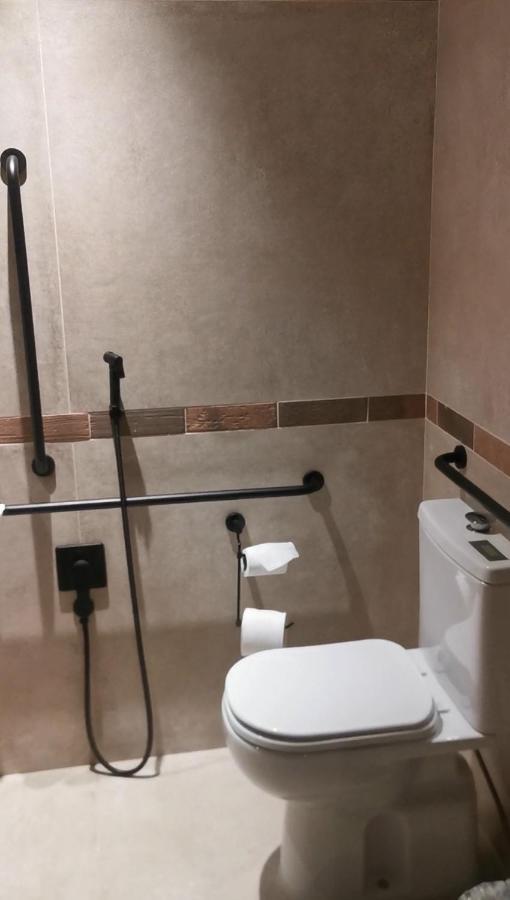 Buona Vitta Gramado Resort & Spa By Gramado Parks Exterior photo The photo shows a bathroom equipped with grab bars for accessibility. The walls are tiled in a neutral color, and there is a toilet on the right side of the image. Two rolls of toilet paper are positioned near the toilet, and there are additional ins
