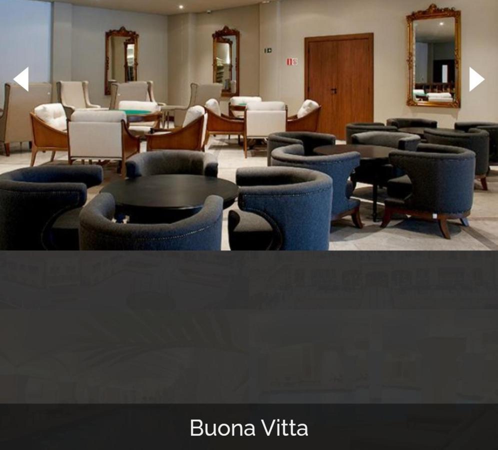 Buona Vitta Gramado Resort & Spa By Gramado Parks Exterior photo The photo shows a modern, elegantly designed lounge or waiting area. It features several circular seating arrangements with dark blue armchairs surrounding black tables. In the background, there are light-colored lounge chairs and a wooden door leadi