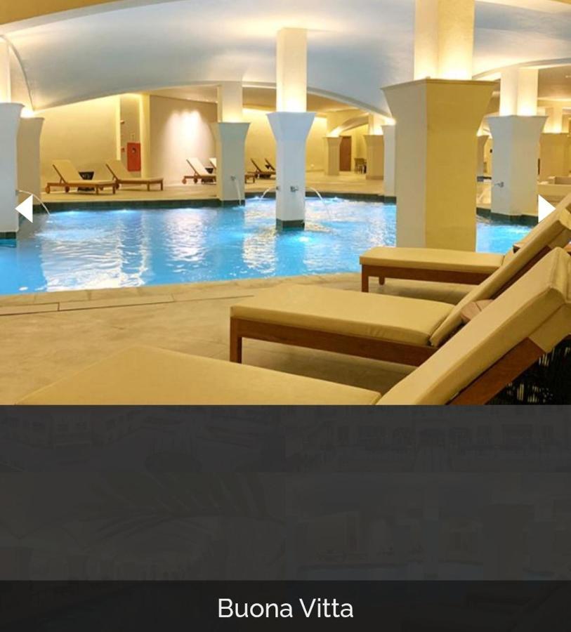 Buona Vitta Gramado Resort & Spa By Gramado Parks Exterior photo The photo shows a tranquil indoor pool area, featuring a large swimming pool with clear blue water. Surrounding the pool are several lounge chairs made of light-colored wood, positioned for relaxation. The space is well-lit, with soft lighting highli