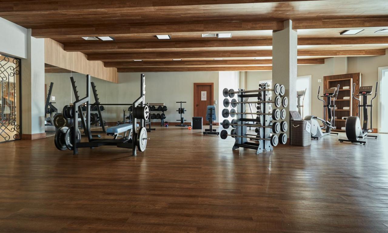 Buona Vitta Gramado Resort & Spa By Gramado Parks Exterior photo The photo shows a spacious gym with a wooden floor and wooden ceiling beams. Various pieces of gym equipment are visible, including weight benches and racks with weights. On one side, there are free weights organized on a rack, while other equipment 