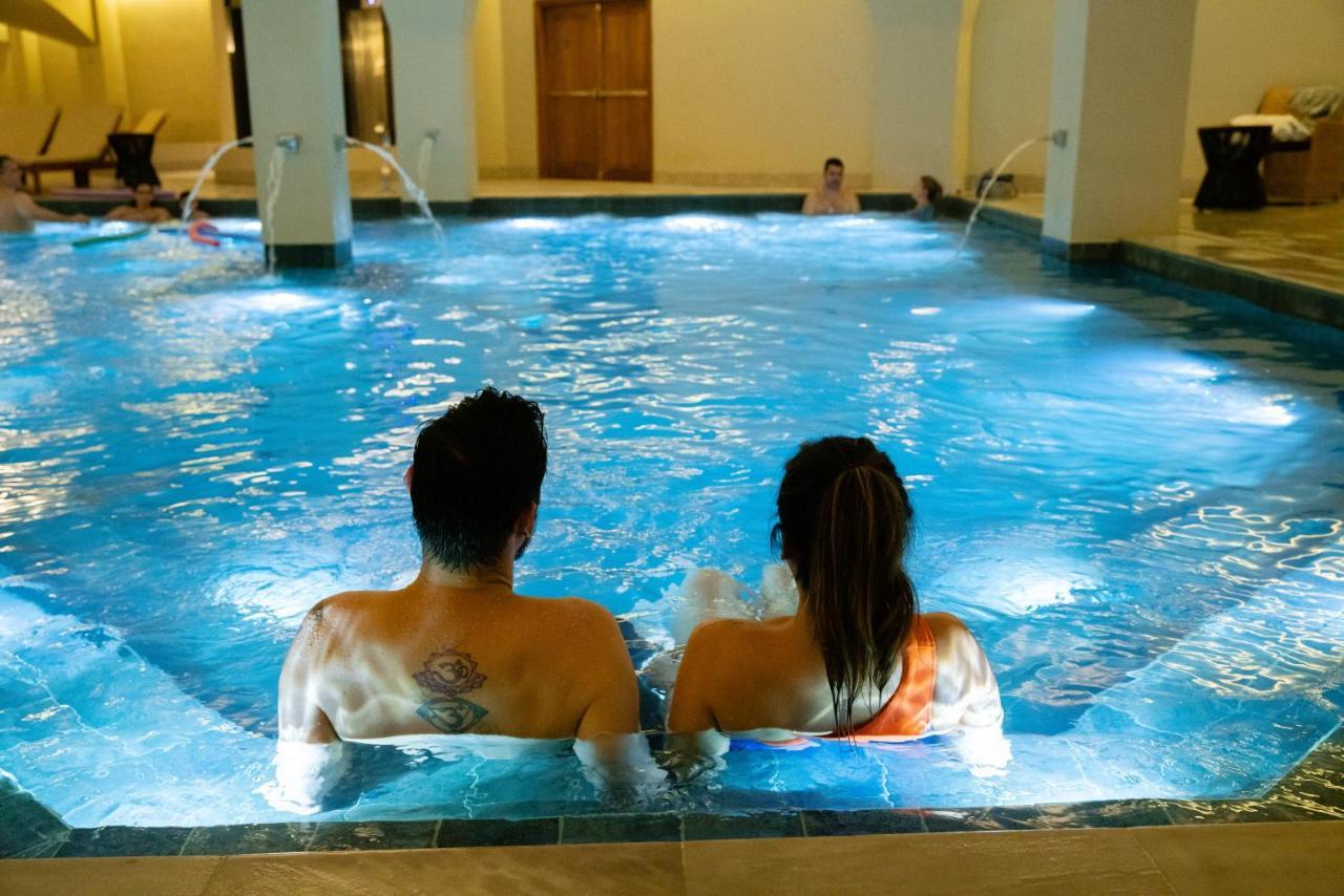 Buona Vitta Gramado Resort & Spa By Gramado Parks Exterior photo The photo shows a couple sitting in a swimming pool with gentle lighting. They are facing away from the camera, appearing relaxed and enjoying their time together. The water is illuminated with a soft blue light, creating a serene atmosphere. In the 