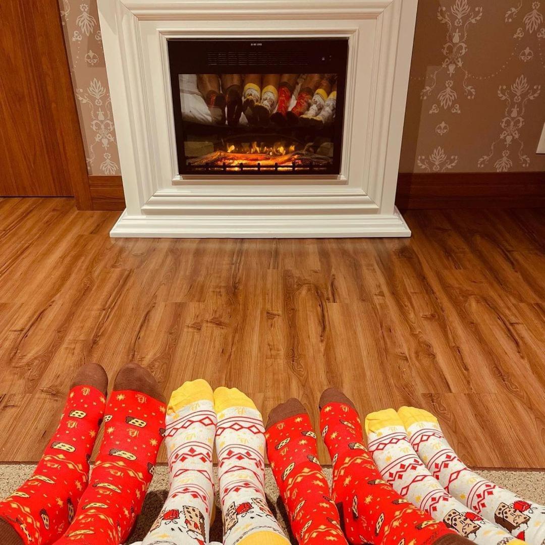 Buona Vitta Gramado Resort & Spa By Gramado Parks Exterior photo The photo shows a cozy indoor setting with a warm fireplace. In the foreground, several pairs of feet are displayed, each wearing brightly colored socks with various patterns. The socks include red, yellow, and white designs, contributing to a cheerf