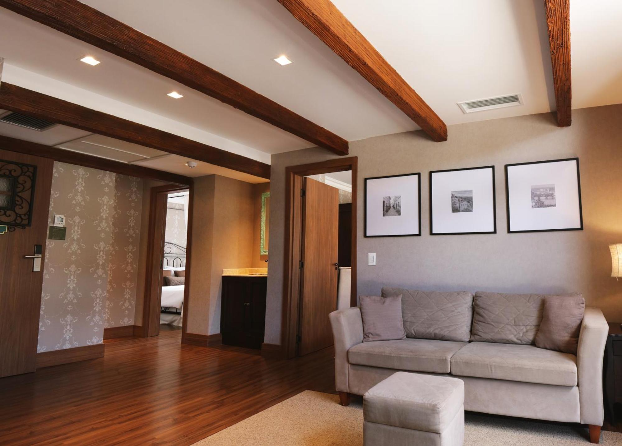 Buona Vitta Gramado Resort & Spa By Gramado Parks Exterior photo The photo showcases a modern living space with a cozy and well-lit atmosphere. There are wooden beams visible on the ceiling, adding a rustic touch. The flooring is a warm-toned wood, contributing to the inviting feel of the room. 

On one side, ther