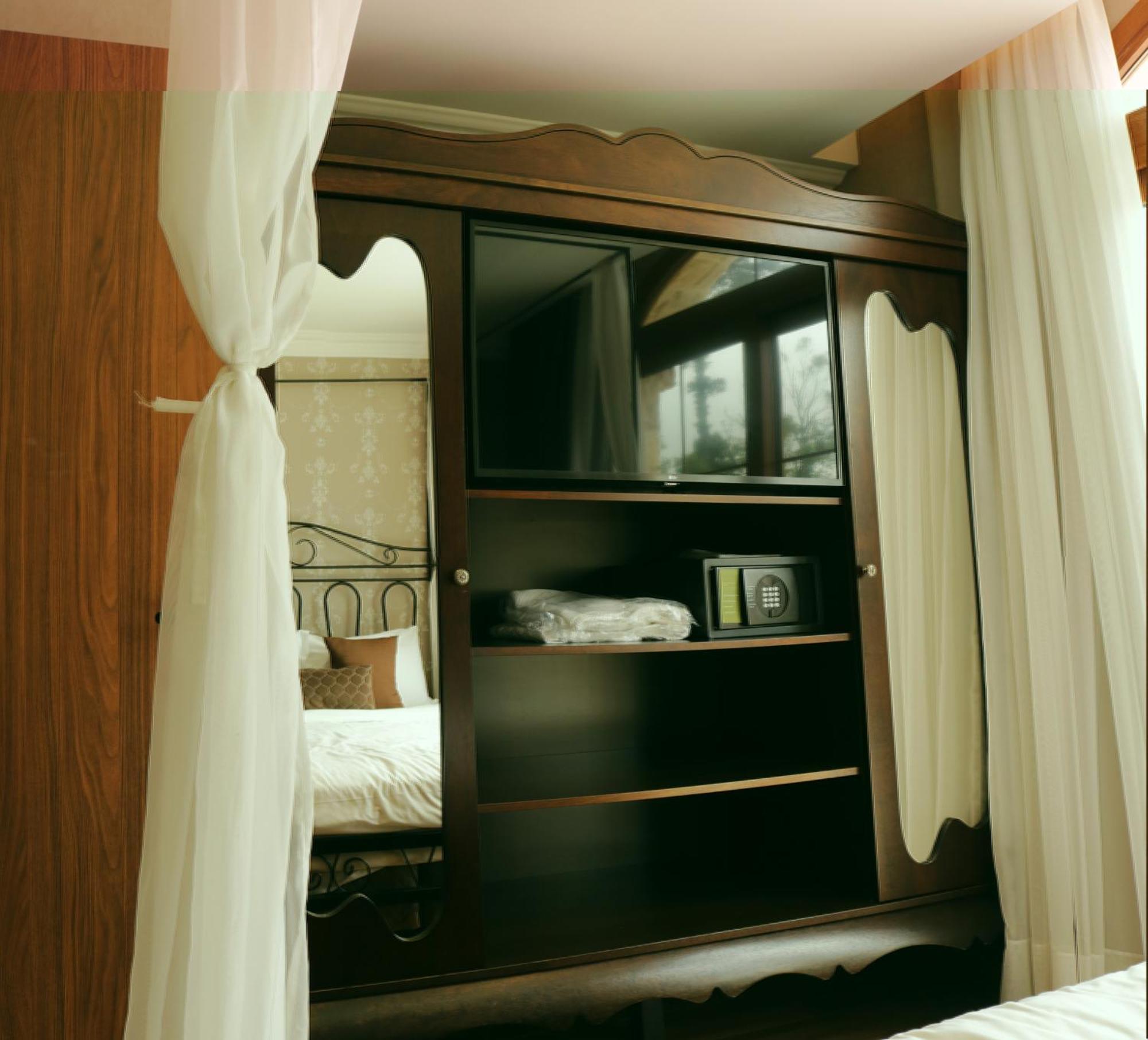 Buona Vitta Gramado Resort & Spa By Gramado Parks Exterior photo The image shows a wooden cabinet with a television mounted on the front. The cabinet has decorative edges and is paired with sheer white curtains on either side. Inside the cabinet, there are shelves, and a small safe or storage box is visible on one