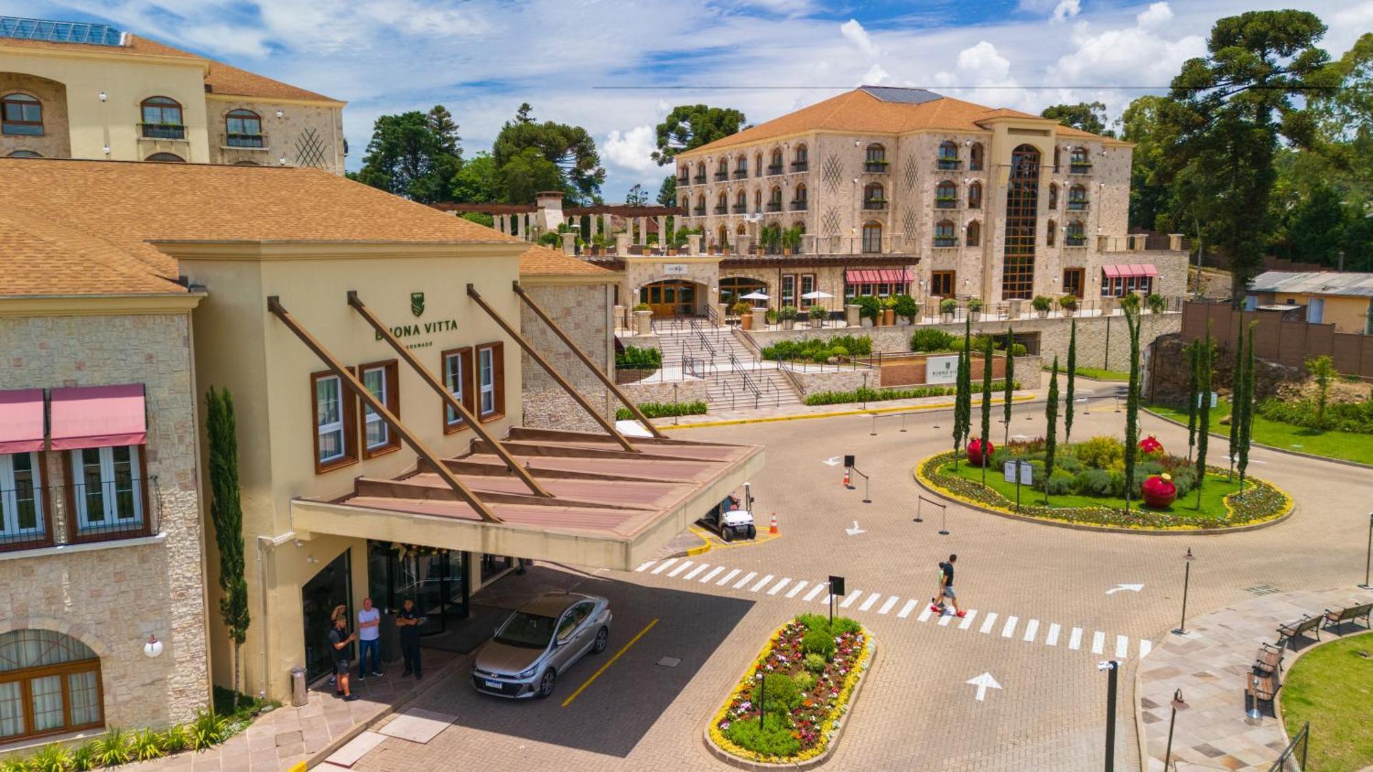 Buona Vitta Gramado Resort & Spa By Gramado Parks Exterior photo The photo shows a luxurious hotel or resort entrance, featuring a modern yet elegant architectural design. In the foreground, there is a covered entrance where vehicles are likely dropping off guests. The building has a stone facade and a welcoming e