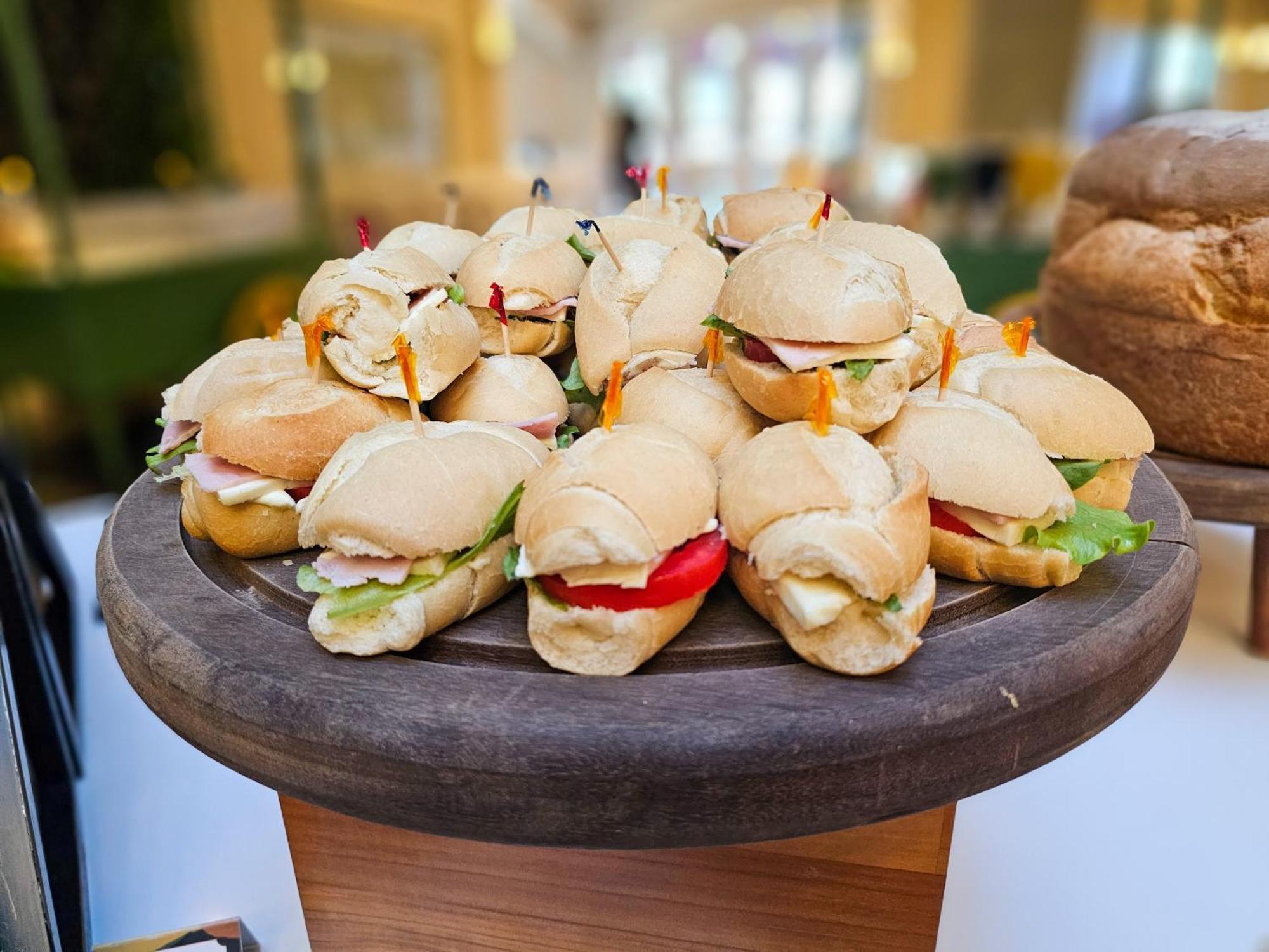 Buona Vitta Gramado Resort & Spa By Gramado Parks Exterior photo The photo shows a platter of small sandwiches, likely sliders, arranged neatly on a wooden serving tray. These sandwiches have various fillings, including what appears to be ham, lettuce, and tomato. They are garnished with colorful toothpicks, and t